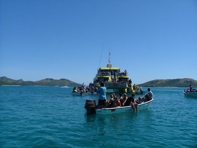 Flotille de barques autour du grand catamaran de liaison inter-îles car souvent il n'y a pas de ports pour débarquer